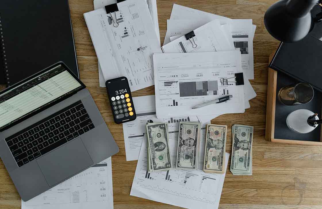 A Laptop Near the Dollars and Papers on a Wooden Table, showing revenue recognition of company